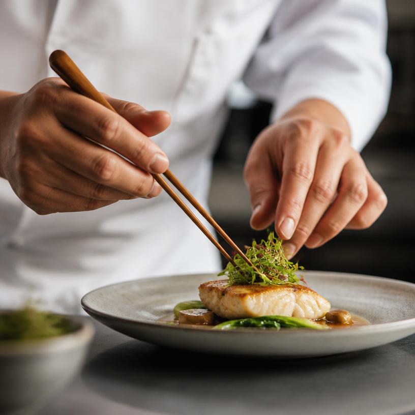 Chef placing greens with chopsticks